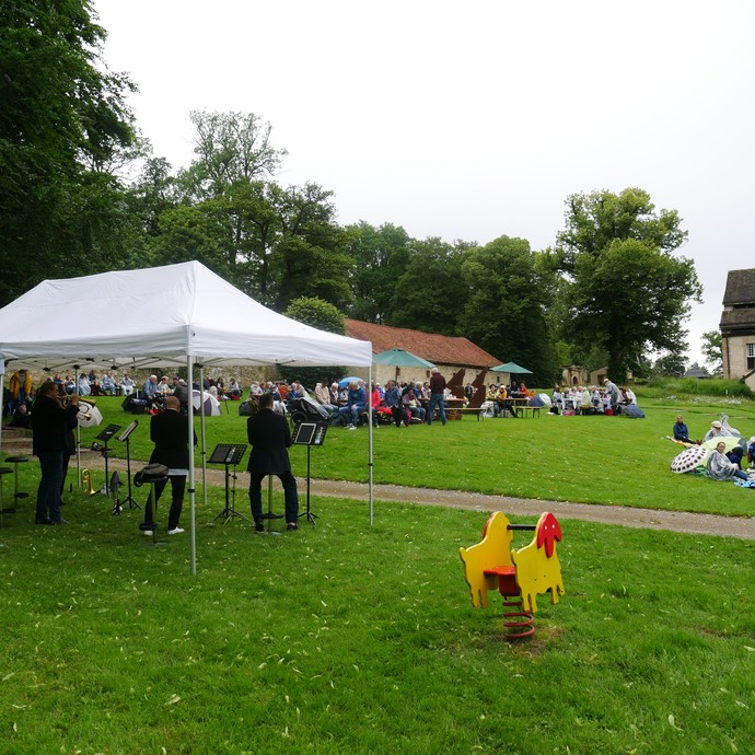 Blick auf den Konventgarten mit Publikum und dem Ensemble Brassfabrik 4.0 beim Picknickkonzert. (vergrößerte Bildansicht wird geöffnet)
