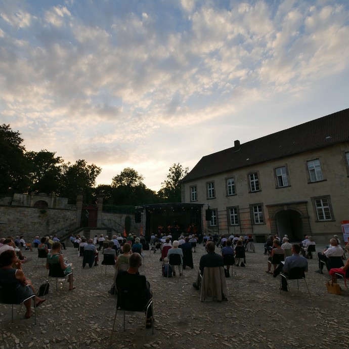 Das Foto zeigt den Ehrenhof im Kloster Dalheim mit Publikum vor einer Bühne. Der Himmel ist strahlend blau. (öffnet vergrößerte Bildansicht)