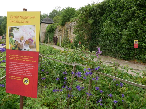 Ein rot-gelbes Schild aus der Gartenausstellung informiert über bienenfreundliche Pflanzen.