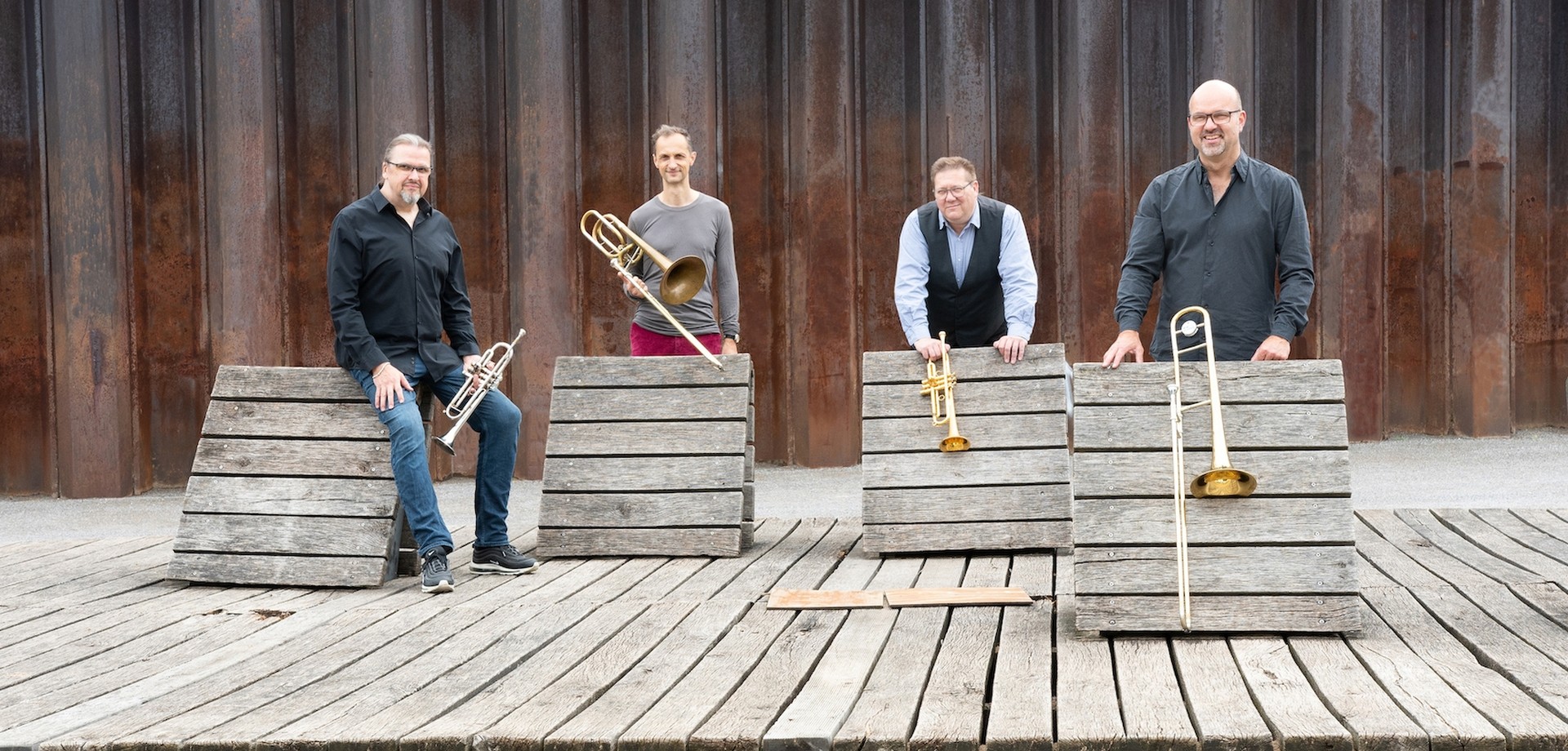 Vier Mitglieder der Band Brassfabrik mit Instrumenten.