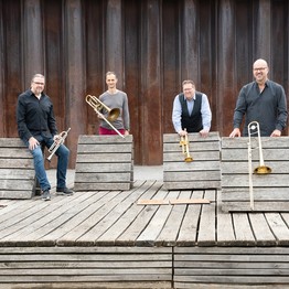 Vier Mitglieder der Band Brassfabrik mit Instrumenten.